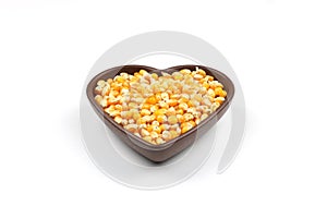 Unpopped popcorn in a wooden bowl on white background. A type of corn that expands from the kernel and puffs up when heated.