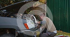Unprofessional car repair. A man repairs a car in an artisanal way.
