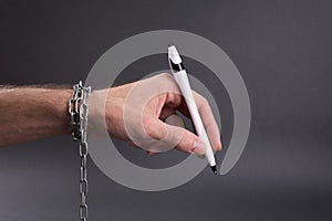 Unprofitable contracts concept, chained hand holding  pen ready to sign