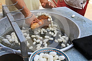 Unraveling White Silkworm Cocoons Floating in Hot Water