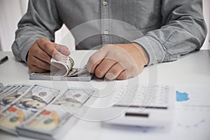 Unrecognisable businessman, accountant, banker counting money at the workplace, white background.