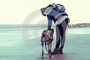 Unrecognisable hipster girl walking her dog, Greyhound, on the beach.