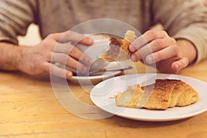 Unrecognisable man having breakfast, eating fresh pastry, with copy space