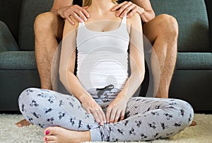 Unrecognisable man sitting on a couch, giving his beautiful wife neck and shoulder massage