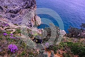 Unrecognisable mountain biker descends on a challenging trail steep towards the sea, Finale Ligure, Italy