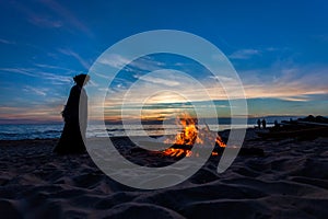 Unrecognisable people celebrating summer solstice with bonfires on beach