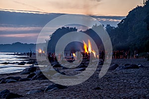 Unrecognisable people celebrating summer solstice with bonfires on beach