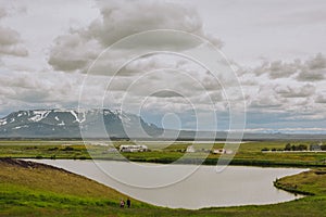 Unrecognisable people on the coastline around the pond Stakholstjorn with pseudo craters - natural monument near Lake Myvatn in