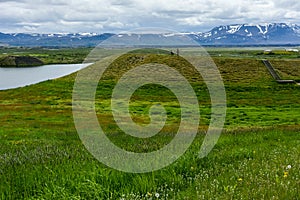 Unrecognisable people on the coastline around the pond Stakholstjorn with pseudo craters - natural monument near Lake Myvatn in