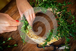 Unrecognisable woman making christmas wreath. DIY Christmas decoration concept. Hands close up.