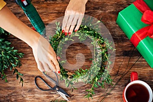 Unrecognisable woman making christmas wreath. DIY Christmas decoration concept. Hands close up top view.