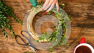Unrecognisable woman making christmas wreath in living room. DIY Christmas decoration concept. Hands close up.
