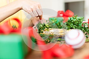 Unrecognisable woman making christmas wreath in living room. DIY Christmas decoration concept. Hands close up.