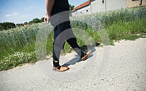 Unrecognisable young men walks on village street in opanci