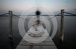 Unrecognised person walking like a ghost at a wooden pier