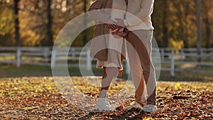 Unrecognised pregnant woman and man hugging, stroking and touching belly and walking outdoors in autumn park. Pregnancy