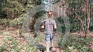 Unrecognizable 7 years boy is hiking in forest in the mountain. Back view. Slow motion.