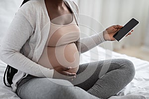 Unrecognizable African American Expectant Mother Using Smartphone With Black Screen At Home