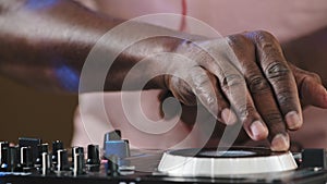 Unrecognizable african american male DJ man professional musician sound engineer with headphones and audio console panel