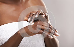 Unrecognizable african american woman applying lotion to her hands, closeup