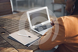 Unrecognizable african american woman sitting at the table in street cafe and using laptop