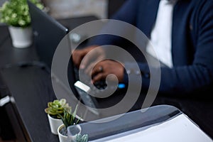 Unrecognizable African businessman working on a black laptop in a modern office