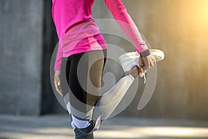 Unrecognizable african lady stretching legs over stoney wall