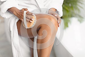 Unrecognizable African Woman Dry Brushing Legs Making Massage In Bathroom