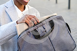 Unrecognizable afro american woman taking laptop out of the bag