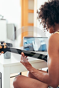 unrecognizable afro american young woman learning to play guitar with online lessons