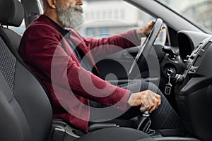 Unrecognizable aged man in suit driving car