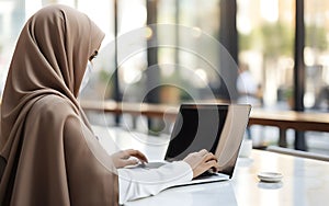 Unrecognizable arab woman in hijab using laptop blank screen in coworking space