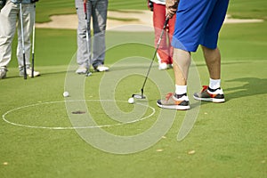 Unrecognizable asian man putting on green in golf course