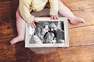 Unrecognizable baby holding family photo. Fathers day.