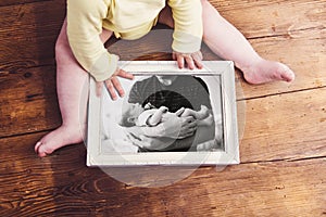 Unrecognizable baby holding picture frame. Fathers day.