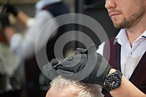 Unrecognizable barber cutting hair of his client in barbershop