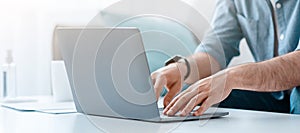 Unrecognizable bearded man working on pc, typing text or programming code on computer keyboard