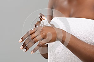Unrecognizable black female applying moisturising lotion to hands