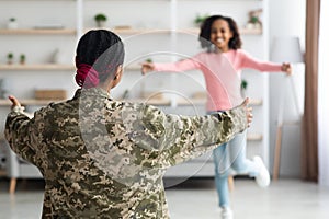 Unrecognizable black girl running towards woman in military uniform