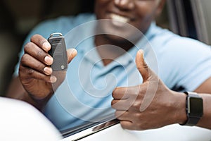 Unrecognizable black man showing car key and thumb up