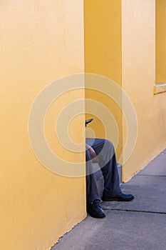 Unrecognizable black man sitting on yellow house front steps looking at phone screen