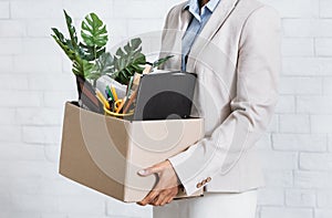 Unrecognizable black woman holding box of personal belongings, leaving office after losing her job, closeup of hands