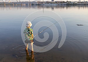 unrecognizable boy fishes standing with fishing rods in the water of the river