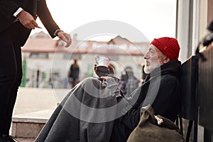 Unrecognizable business man help to beggar homeless man