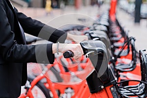 unrecognizable business woman renting a shared electric bike on city street