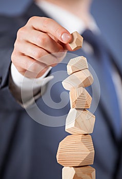 Unrecognizable businessman forming a wooden pyramid