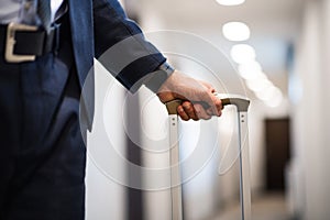 Unrecognizable businessman with luggage in a hotel corridor.