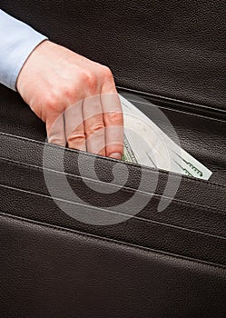 Unrecognizable businessman puts money in a briefcase