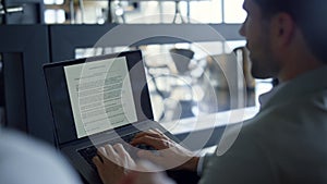 Unrecognizable businessman work laptop at dark office. Man hands typing keyboard