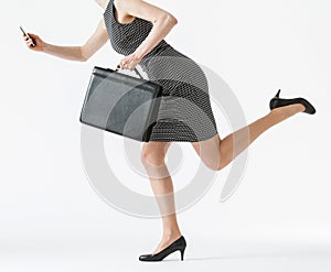 Unrecognizable businesswoman running and holding her cellphone a